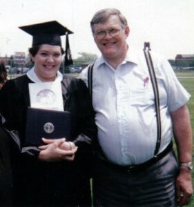 Picture of author in college graduation cap and gown. Standing next to her is her dad. Both are smiling broadly.